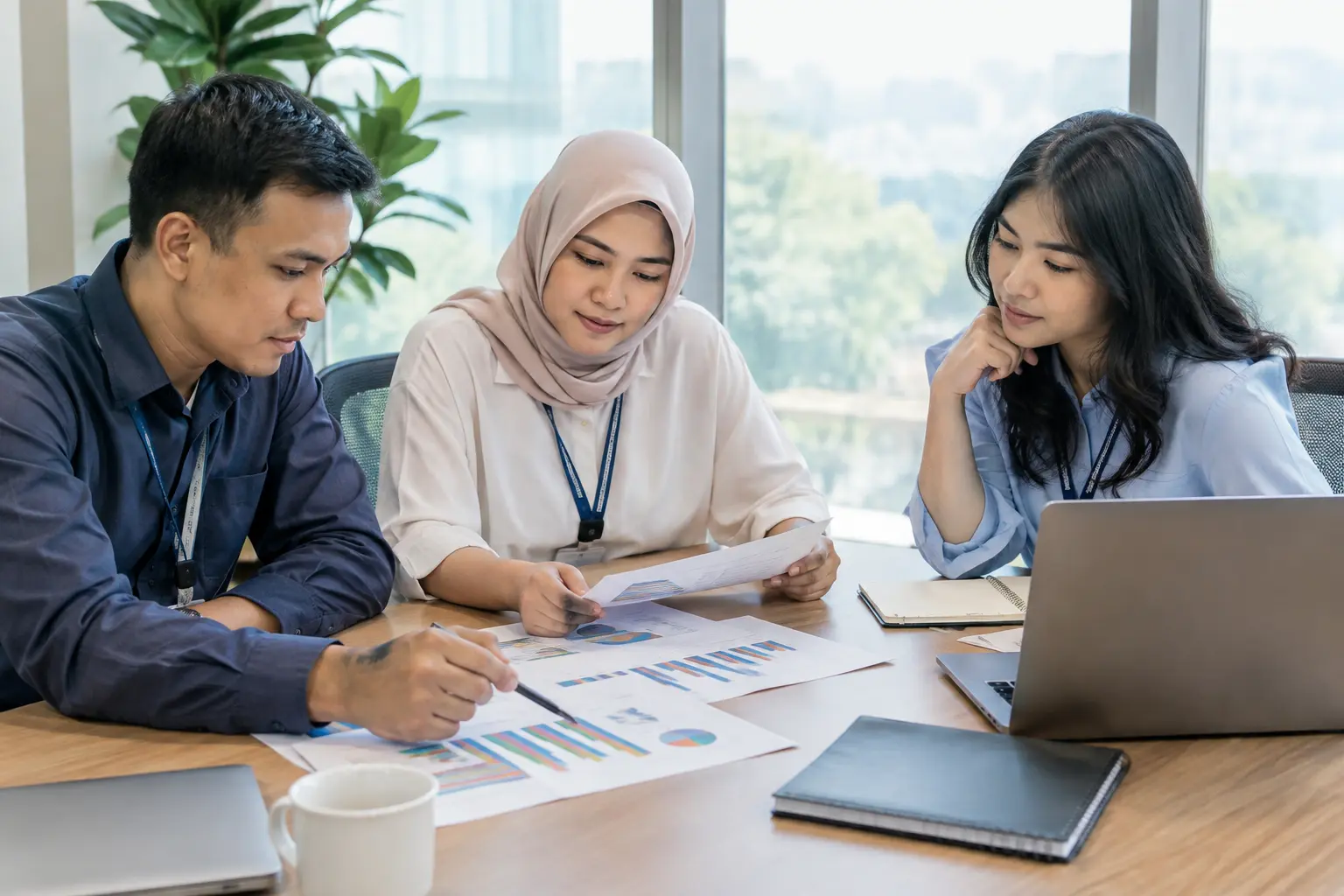 Staf SDM meninjau grafik hasil survei karyawan di meja ruang rapat